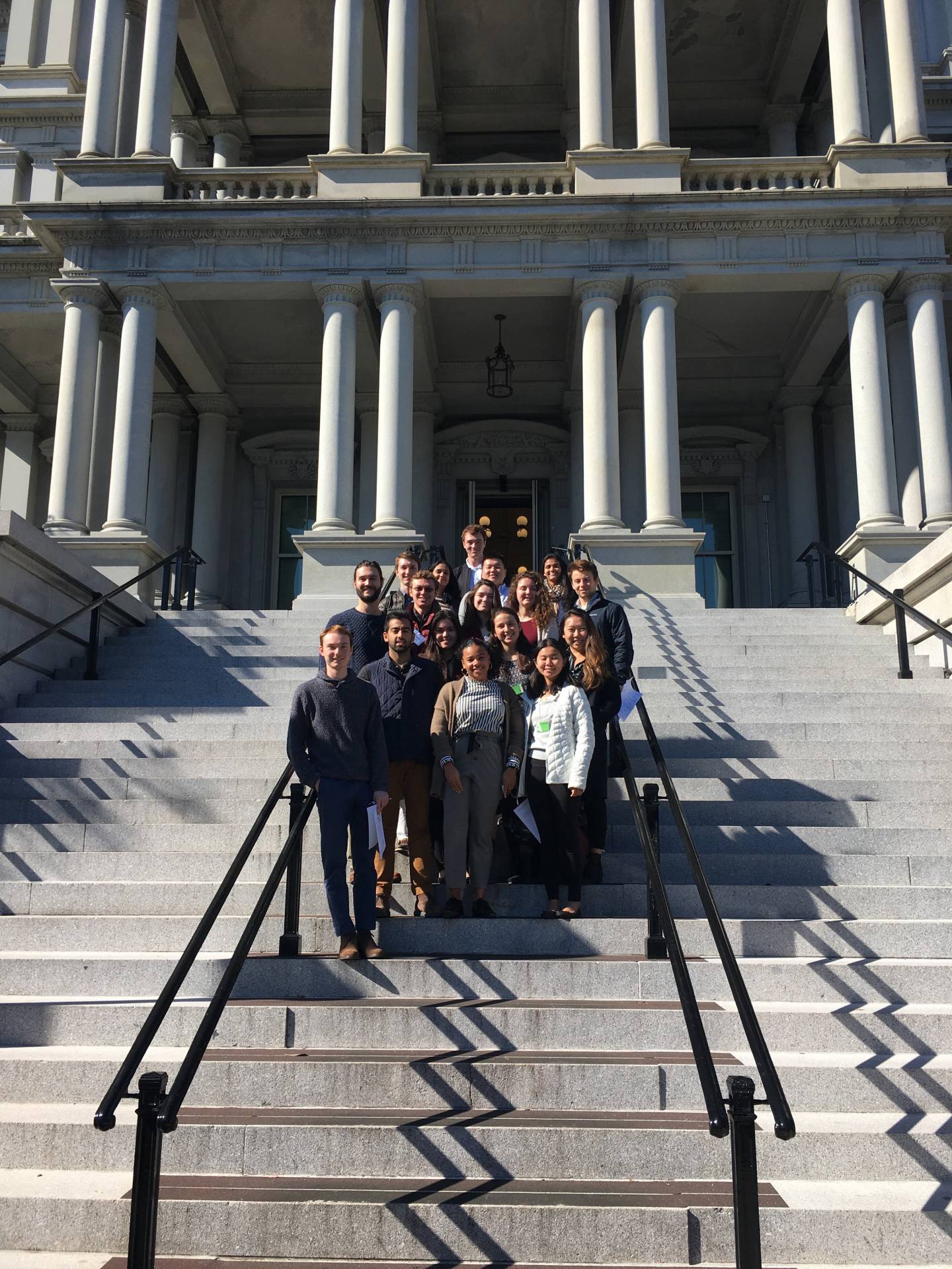 A group of students pose for a photo on the steps of the Eisenhower Executive Office Building in Washington DC