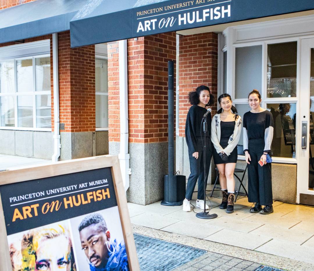 Three students sing at a microphone outside the Art on Hulfish gallery
