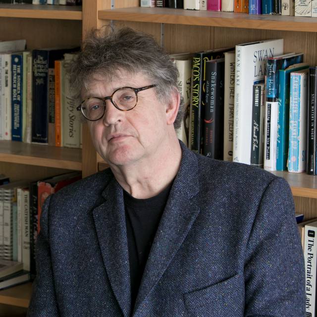 Paul Muldoon with bookshelves in background