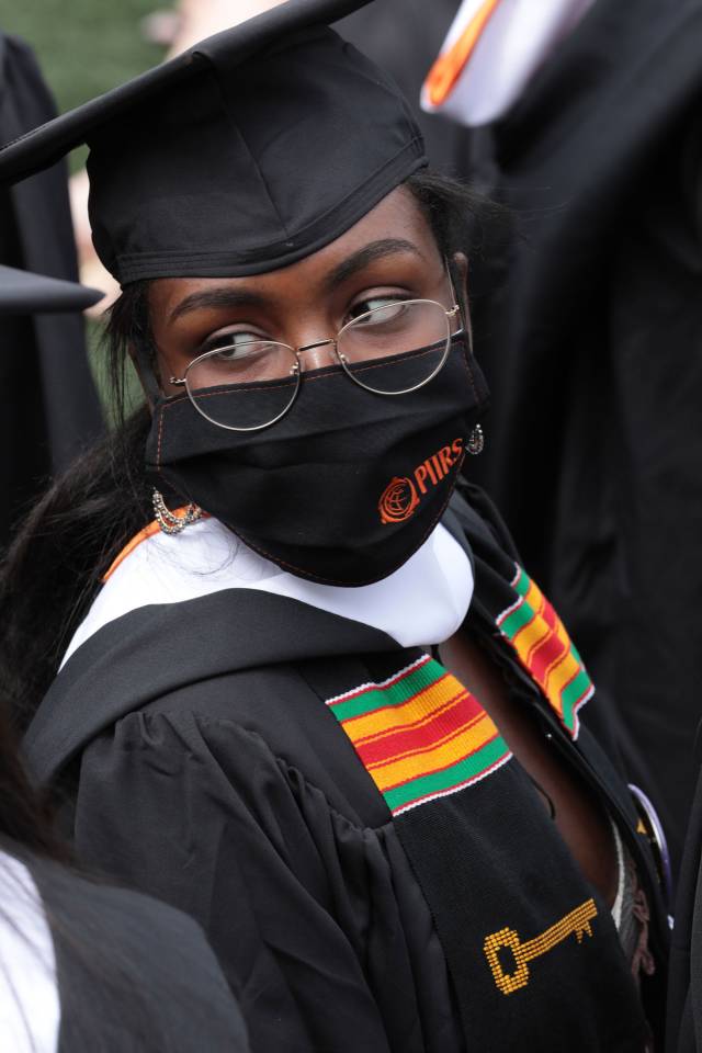 A graduating student wearing a Pan-African scarf and a PIIRS mask