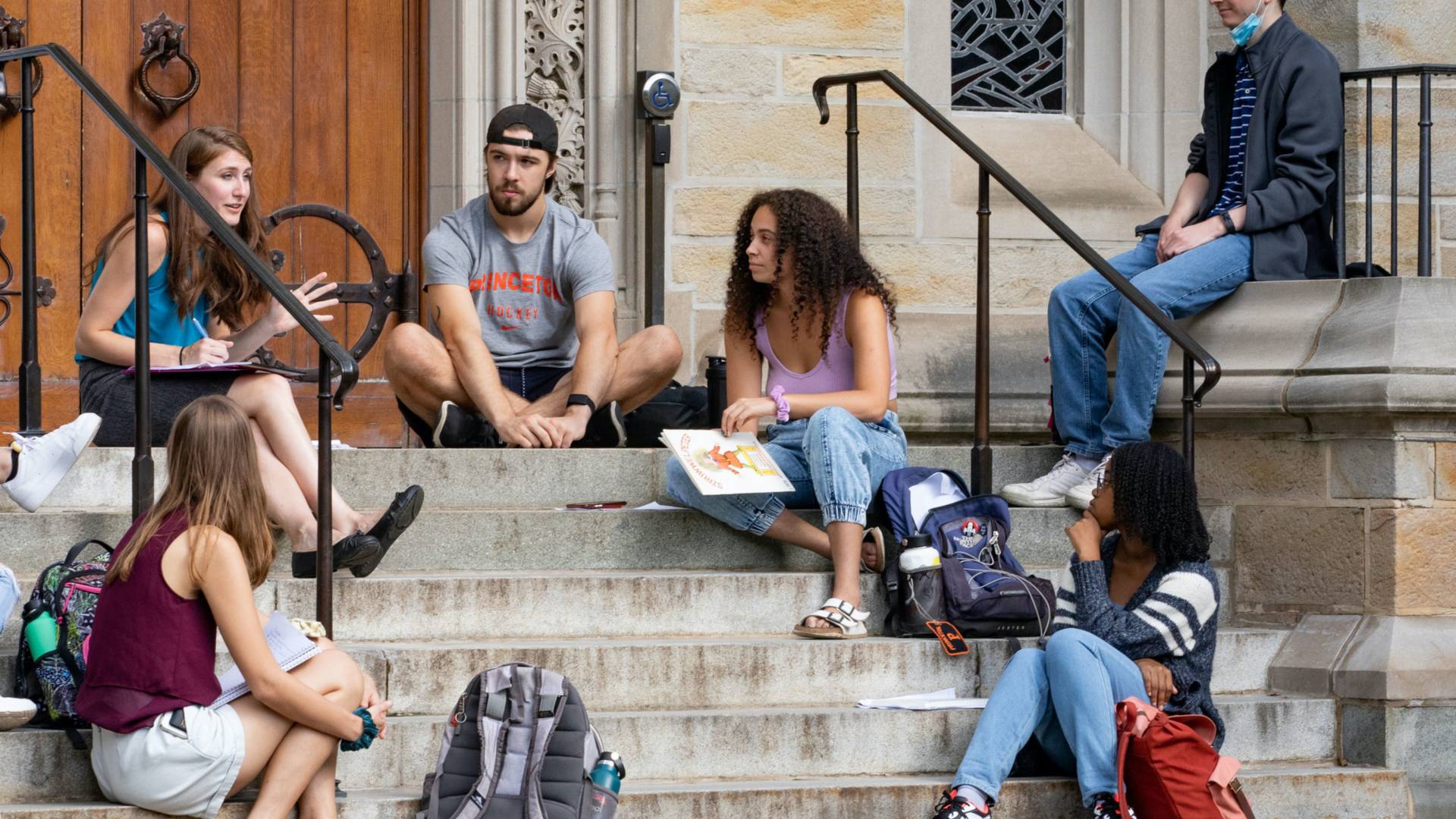 Students having a discussion on steps outside a building.