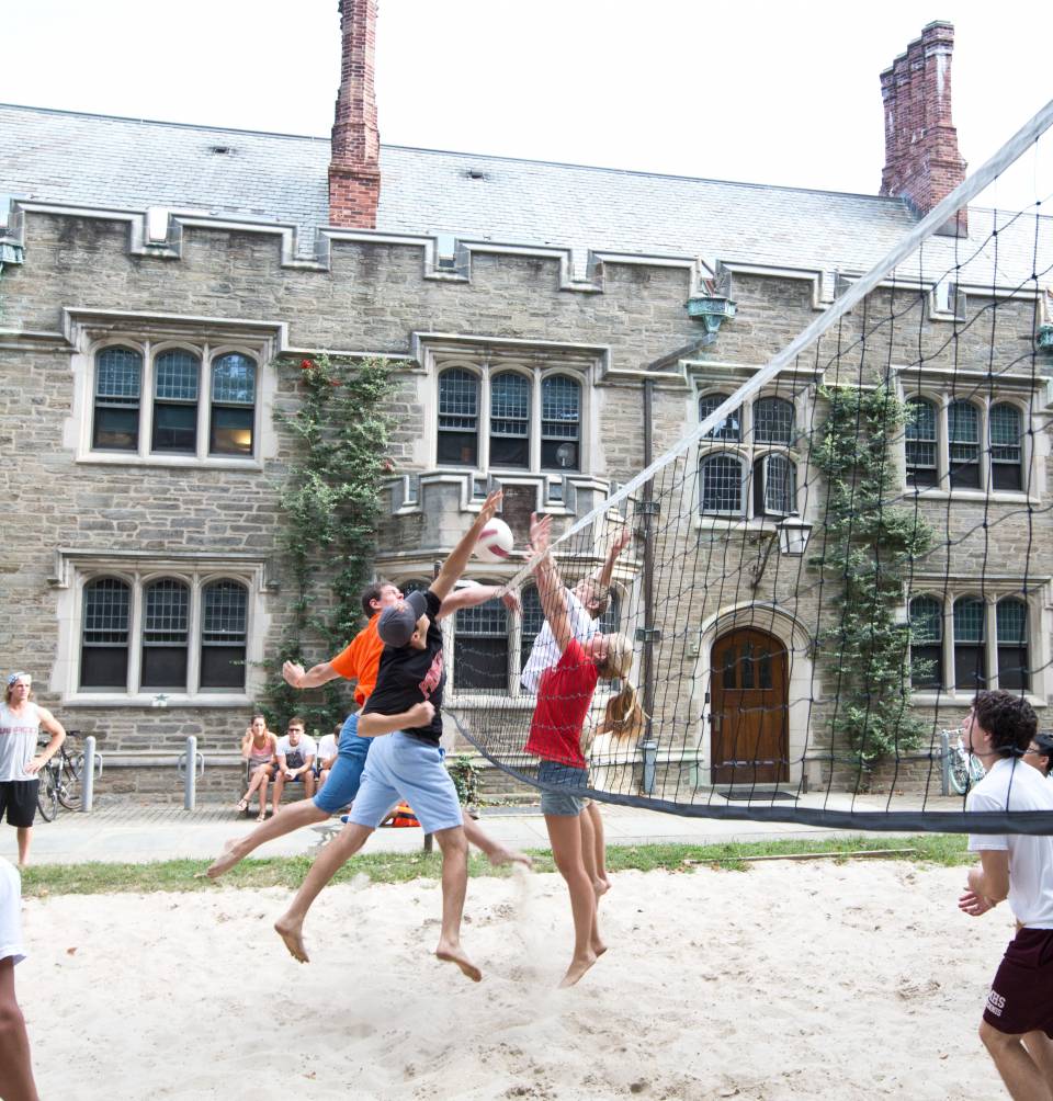 Students playing volleyball on sand court