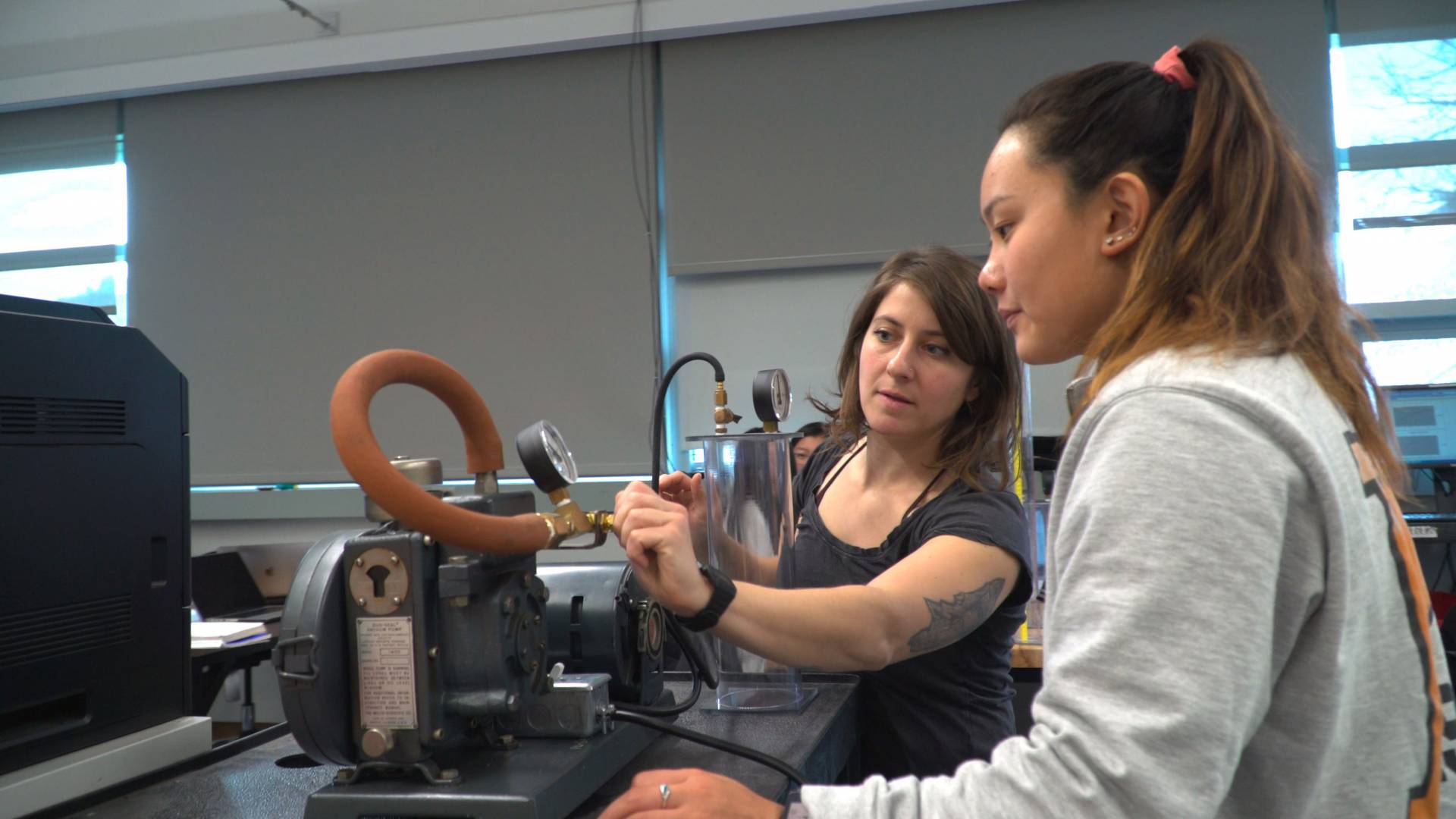 Instructor working with student in physics lab