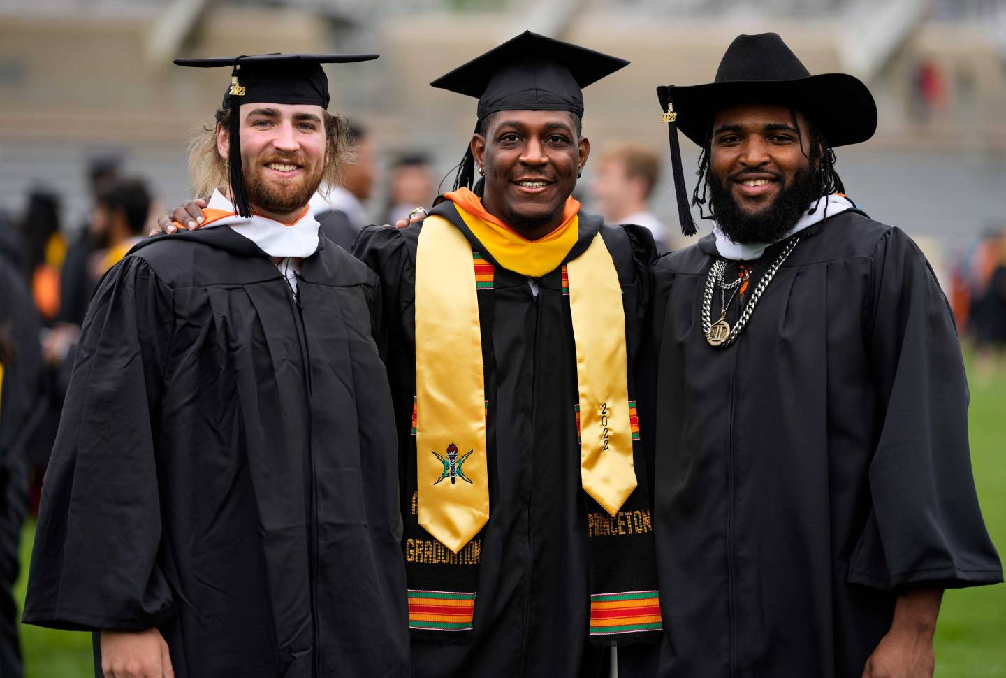 3 football players in their graduation regalia
