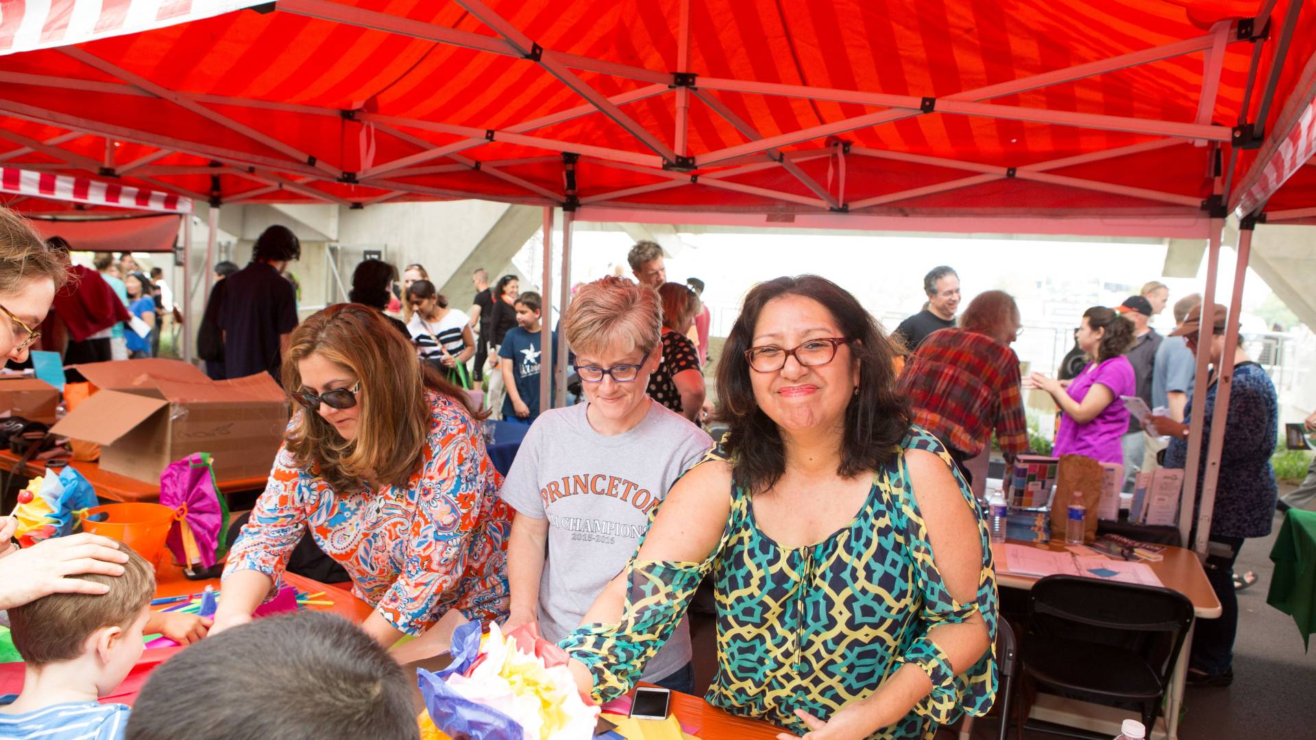 Photo of staff and faculty volunteers helping children at an art booth.