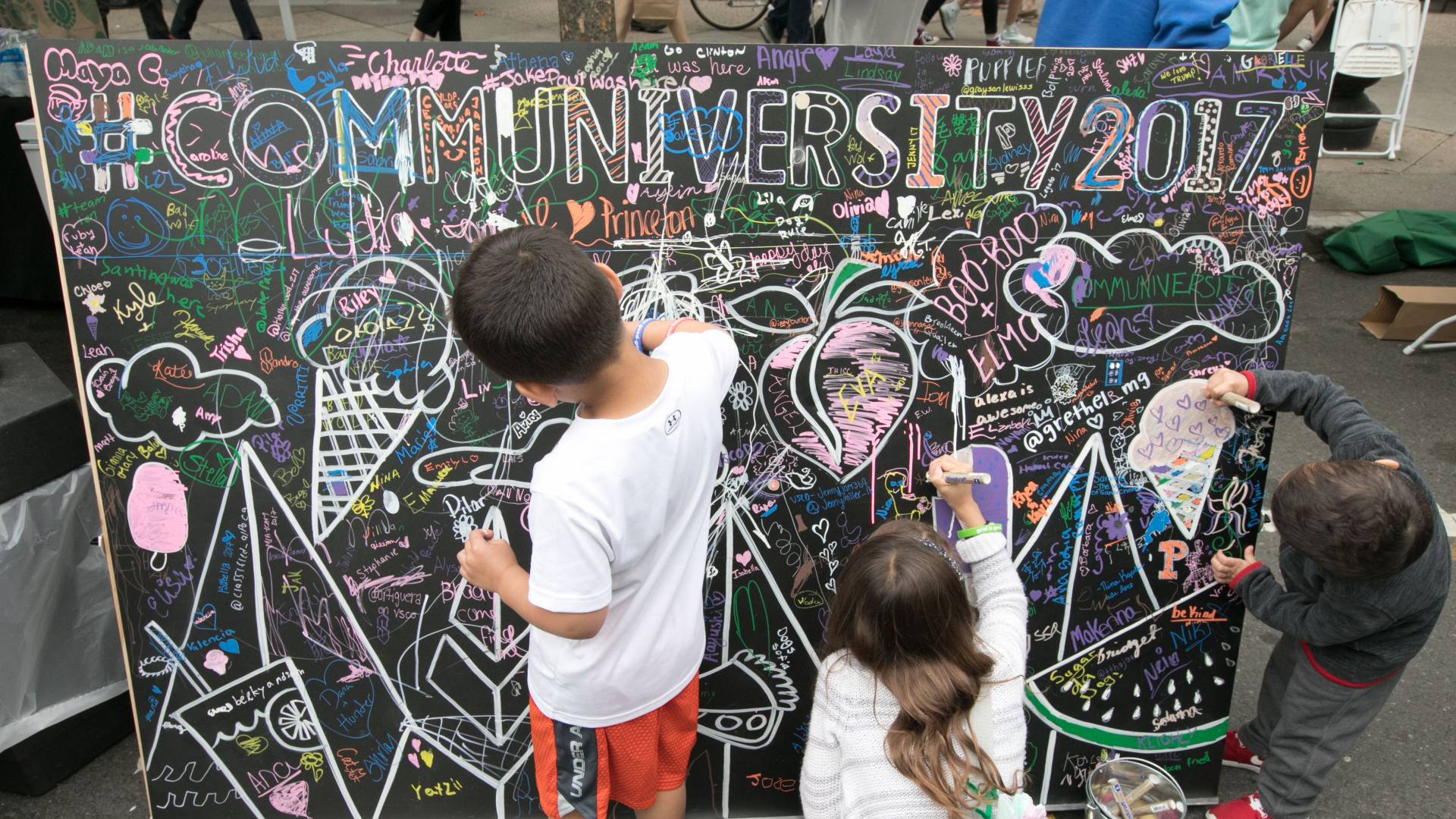 The annual Communiversity Artsfest includes arts and crafts demonstrations and activities ranging from tissue paper flowers to oil painting. Above, children add their own artistic flourishes to a Communiversity sign. 