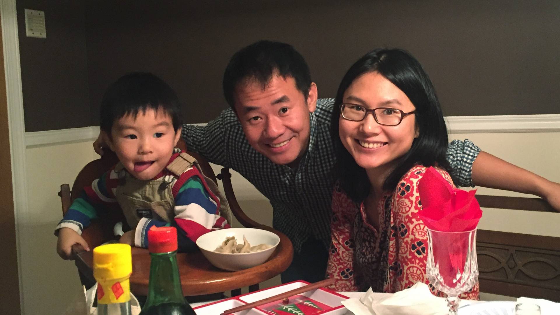 Xiyue Wang, Hua Qu and their son seated at a table