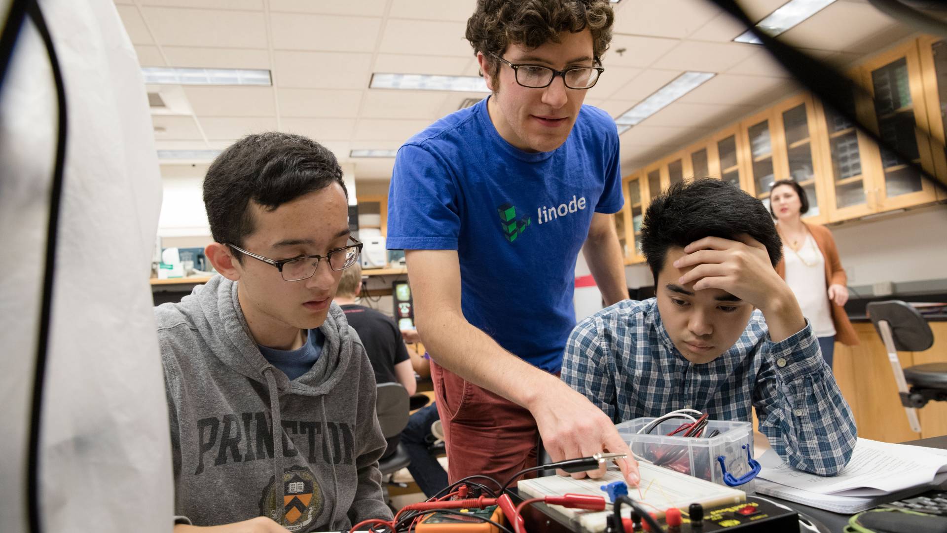 Students working with graduate student on circuit board