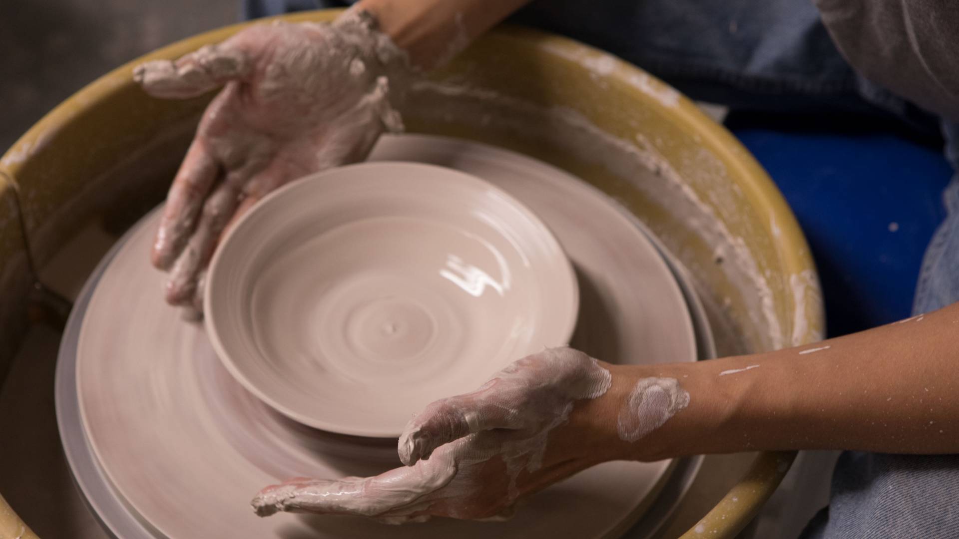hands shaping clay bowl on wheel