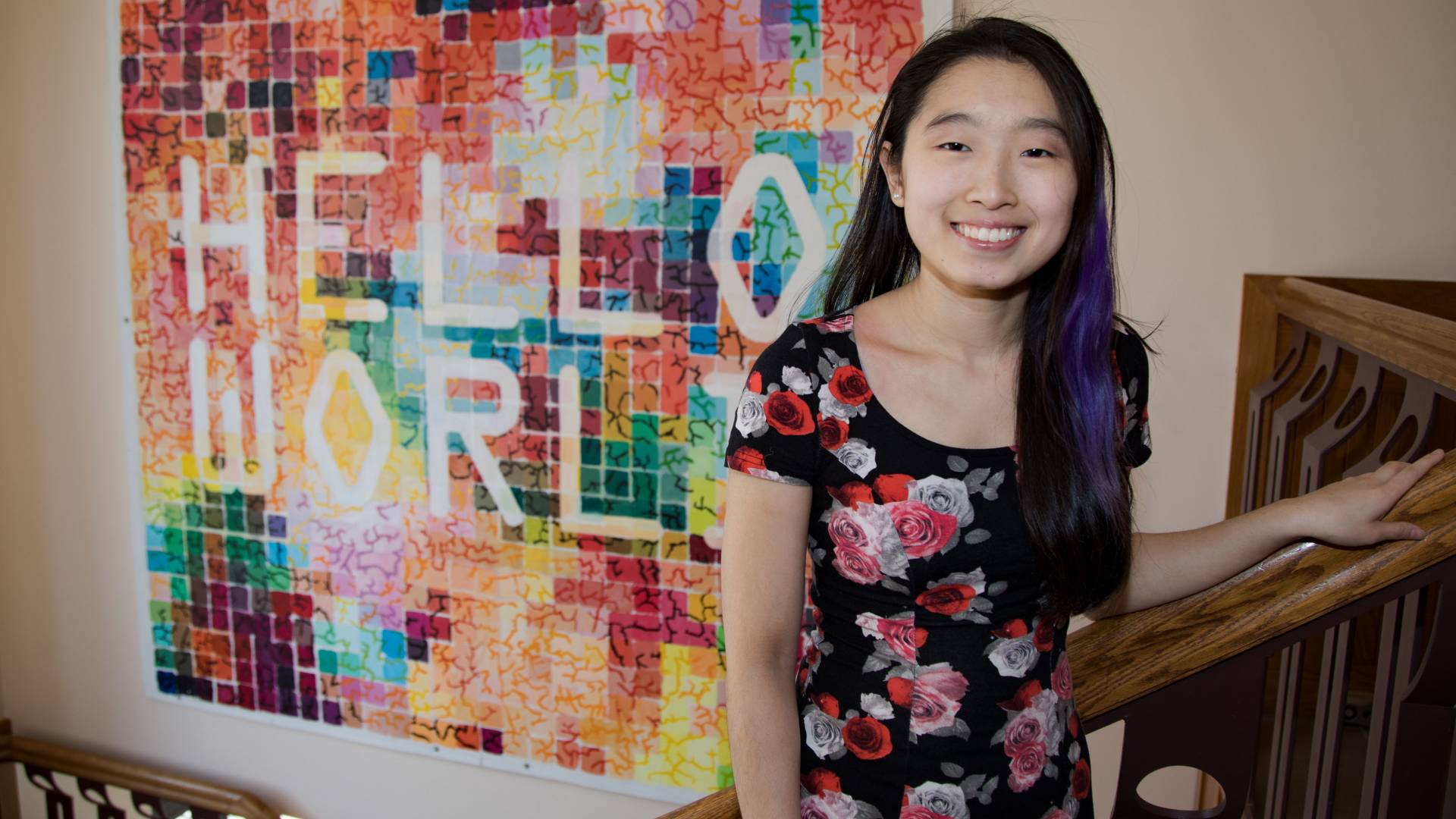 Katherine Lim standing in stairwell in front of Hello World mural