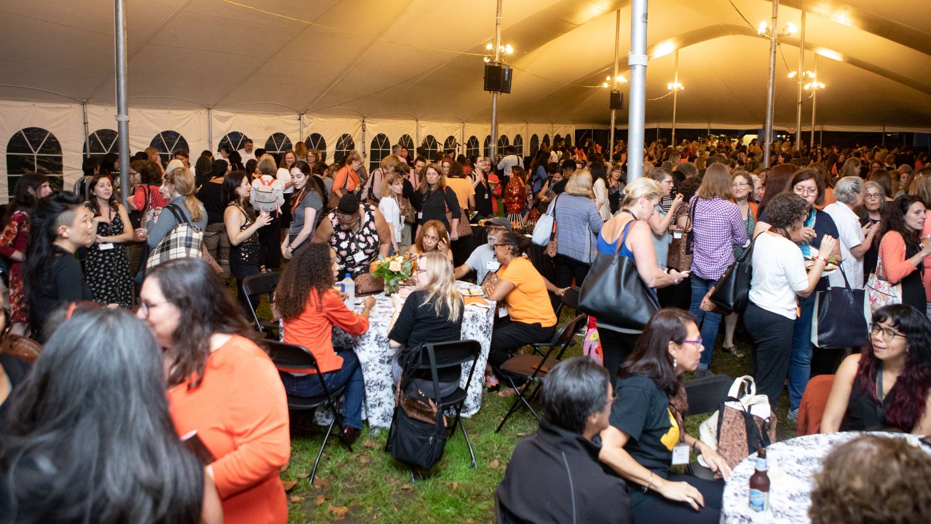 Alumnae gathering under tent during opening reception