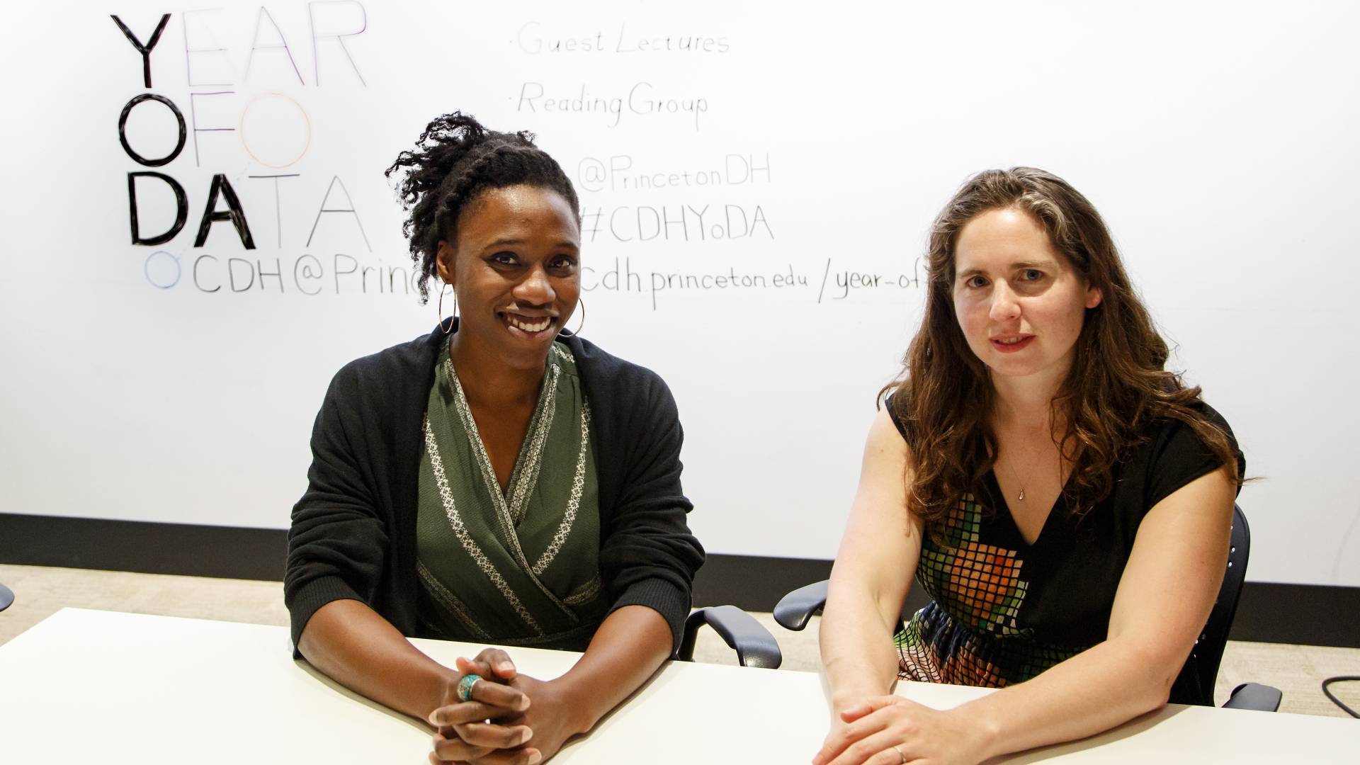 Mimi Onuoha (left) and Lauren Klein sit at table with "Year of Data " on white board behind them