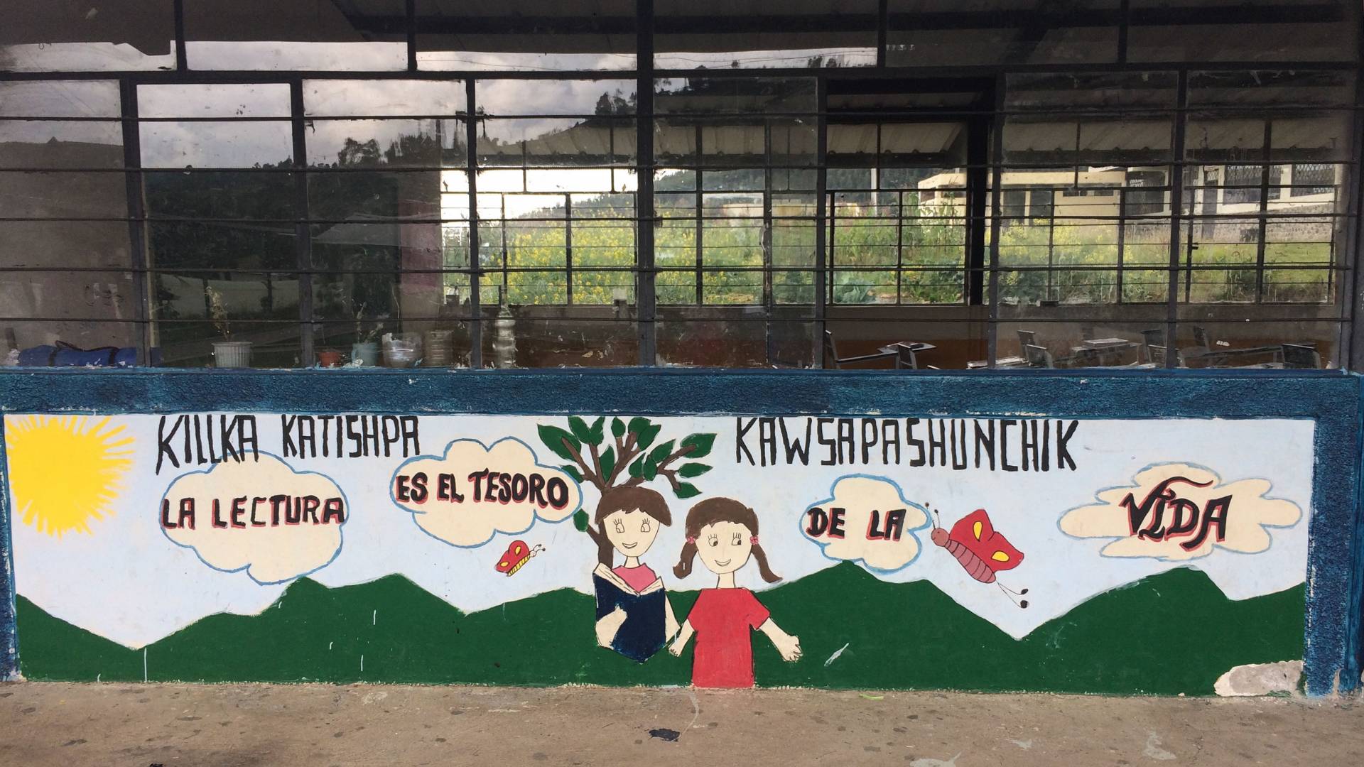 Painted mural on wall in Ecuador that says “La lectura es el tesoro de la vida”