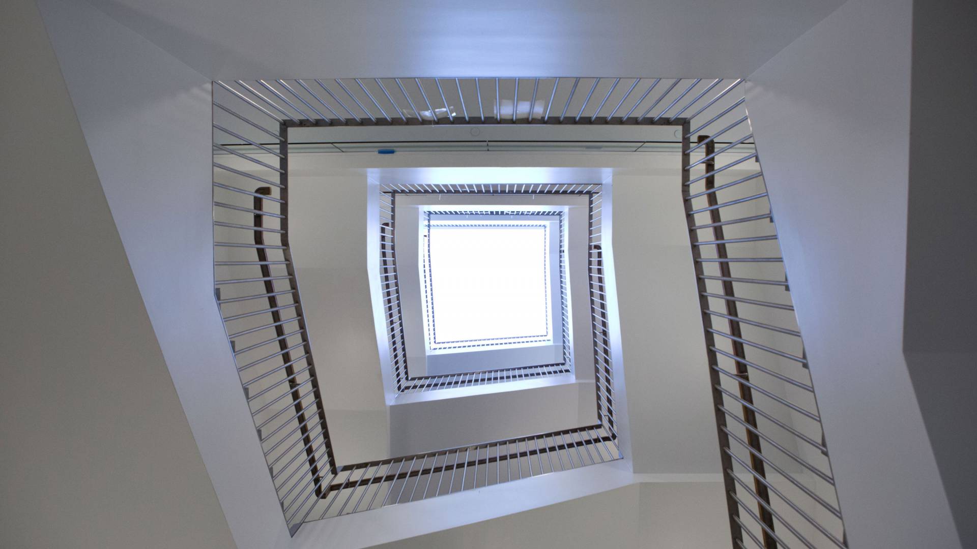 Looking up at a skylight surrounded by a staircase