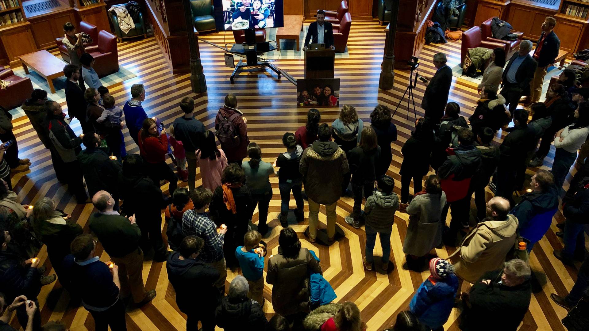 A crowd stands listening to a speaker at a podium in Chanceloor Green.