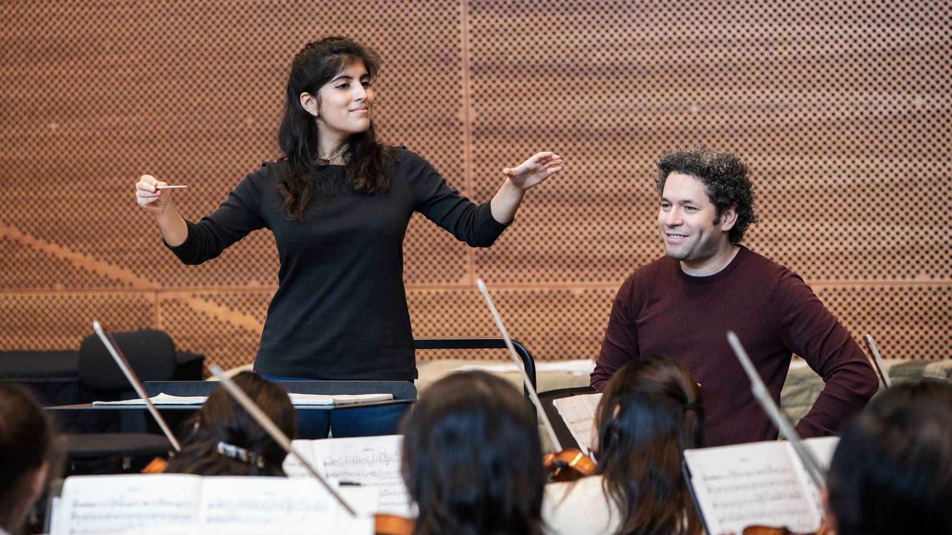 Mariana Corichi Gomez conducting orchestra in front of Gustavo Dudamel