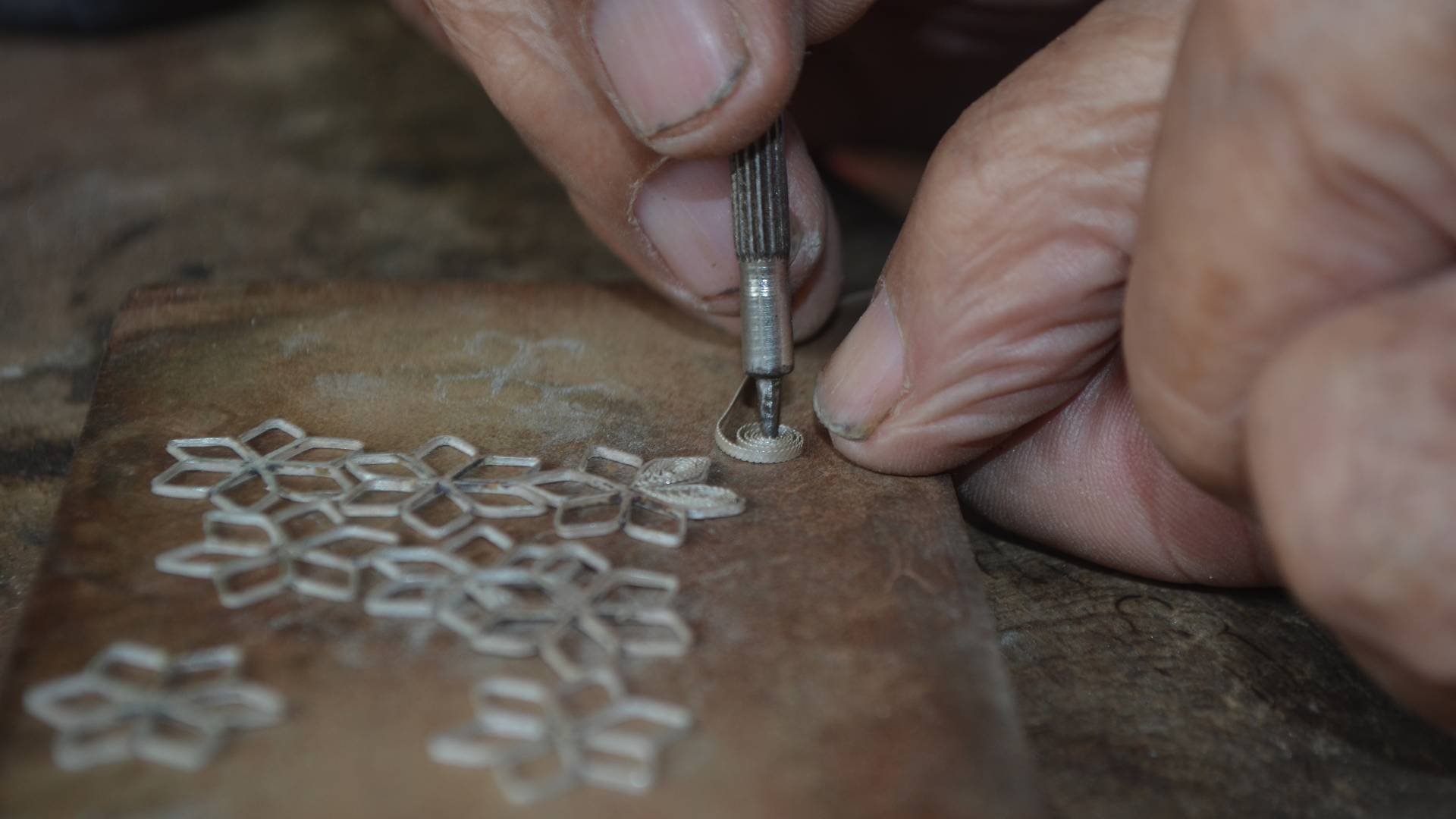 Close up of man's hands working with filigree tool