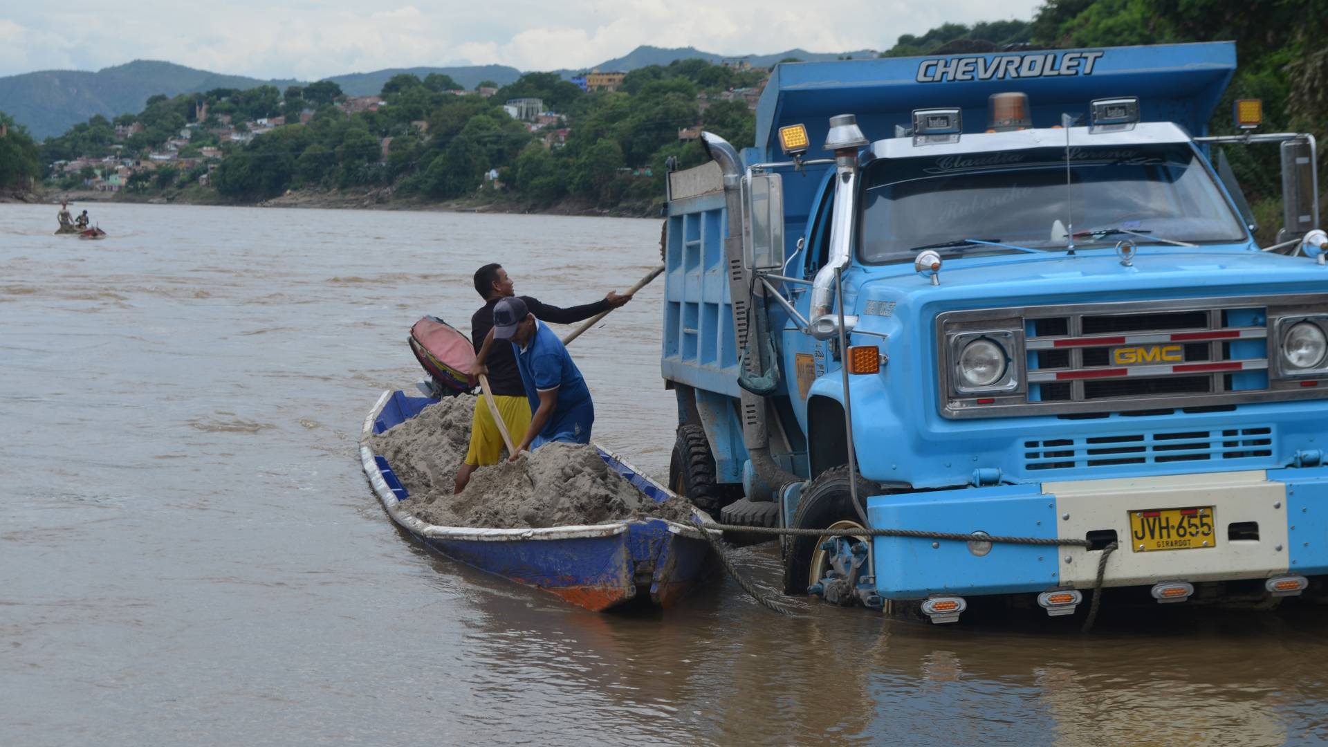 Men putting silt from river into dump truck