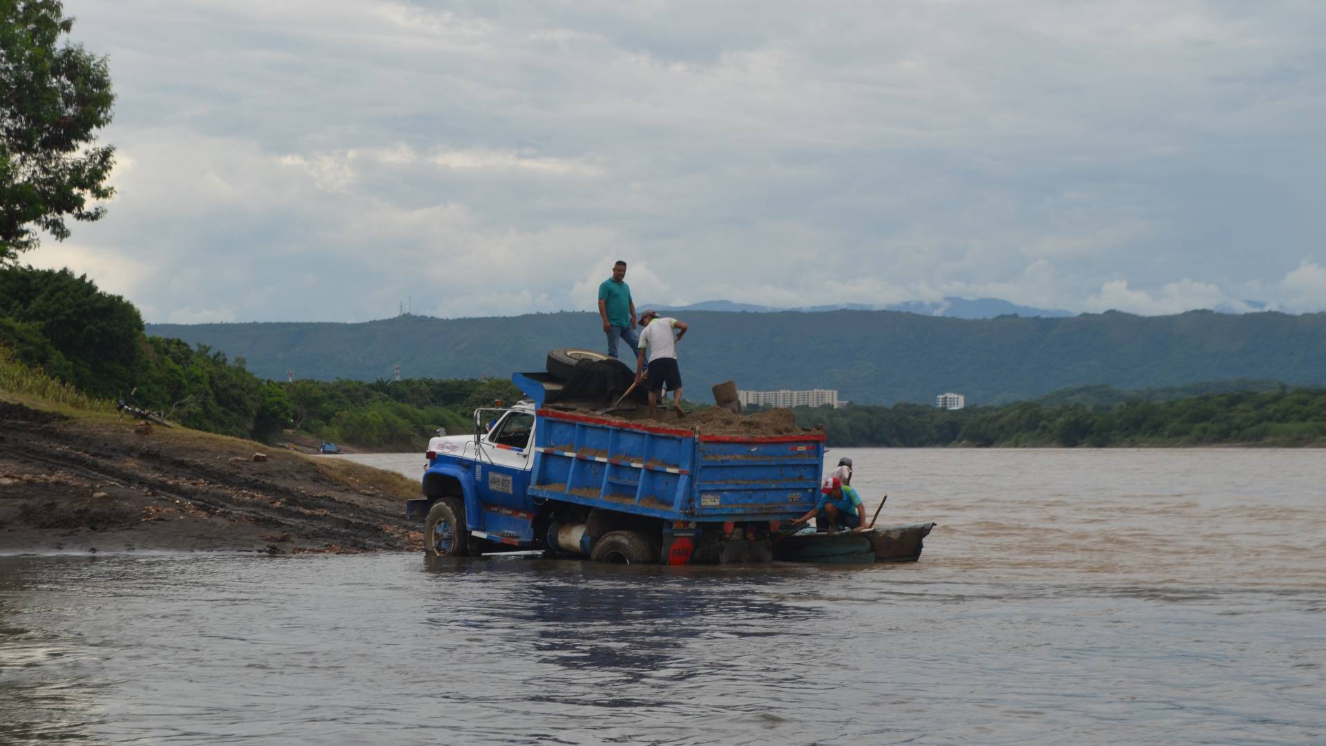 Men on dump truck in river