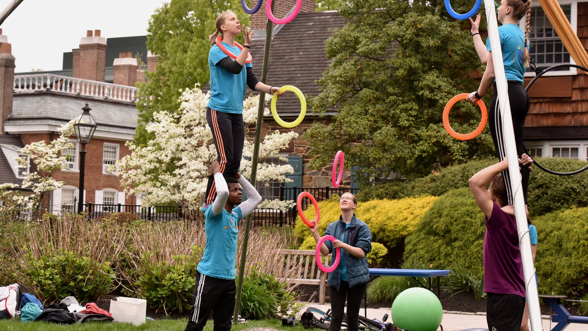 2 women juggling colorful rings while standing on the shoulders of 2 young men