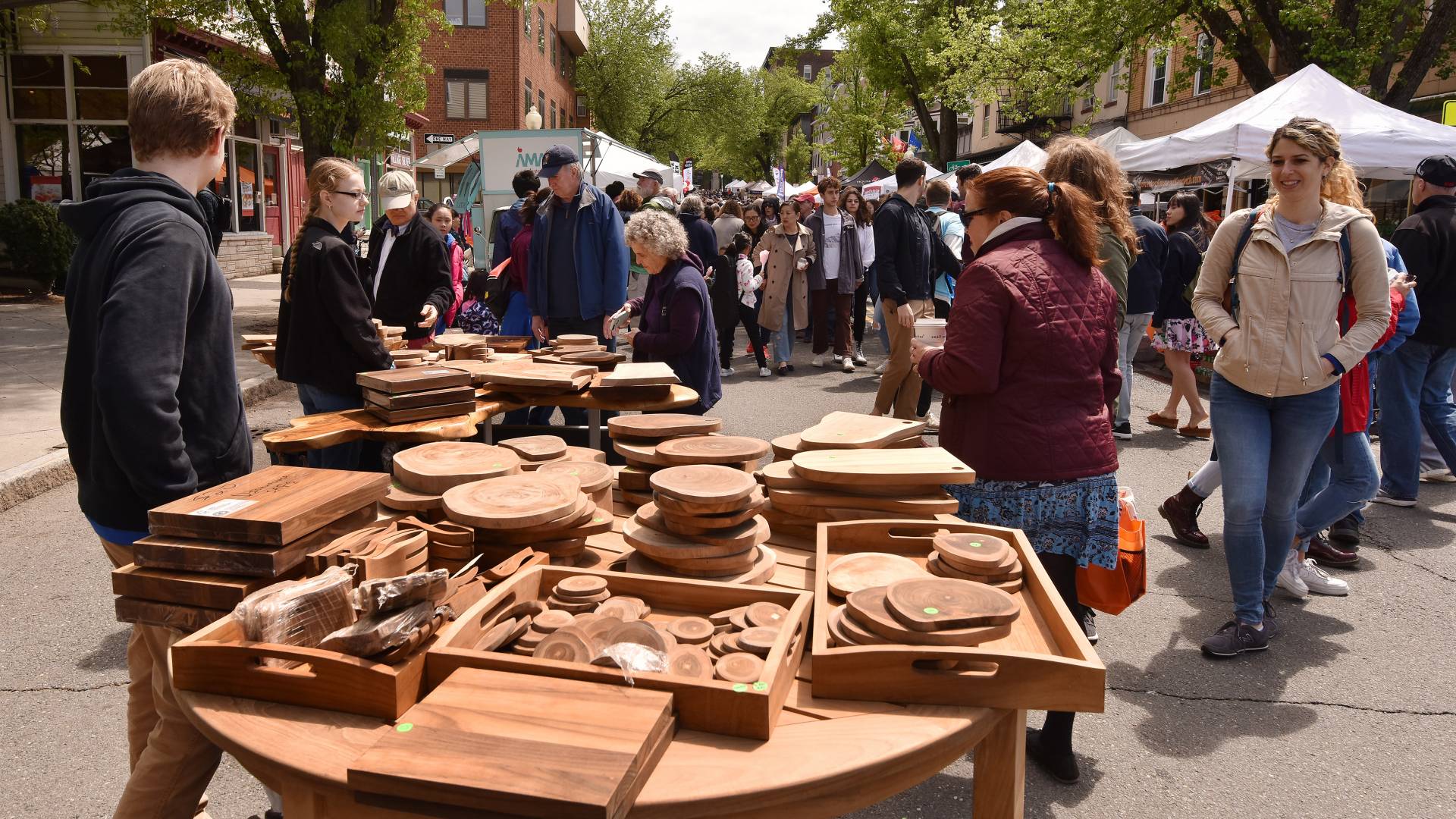 Wood crafts at a table while people walk 