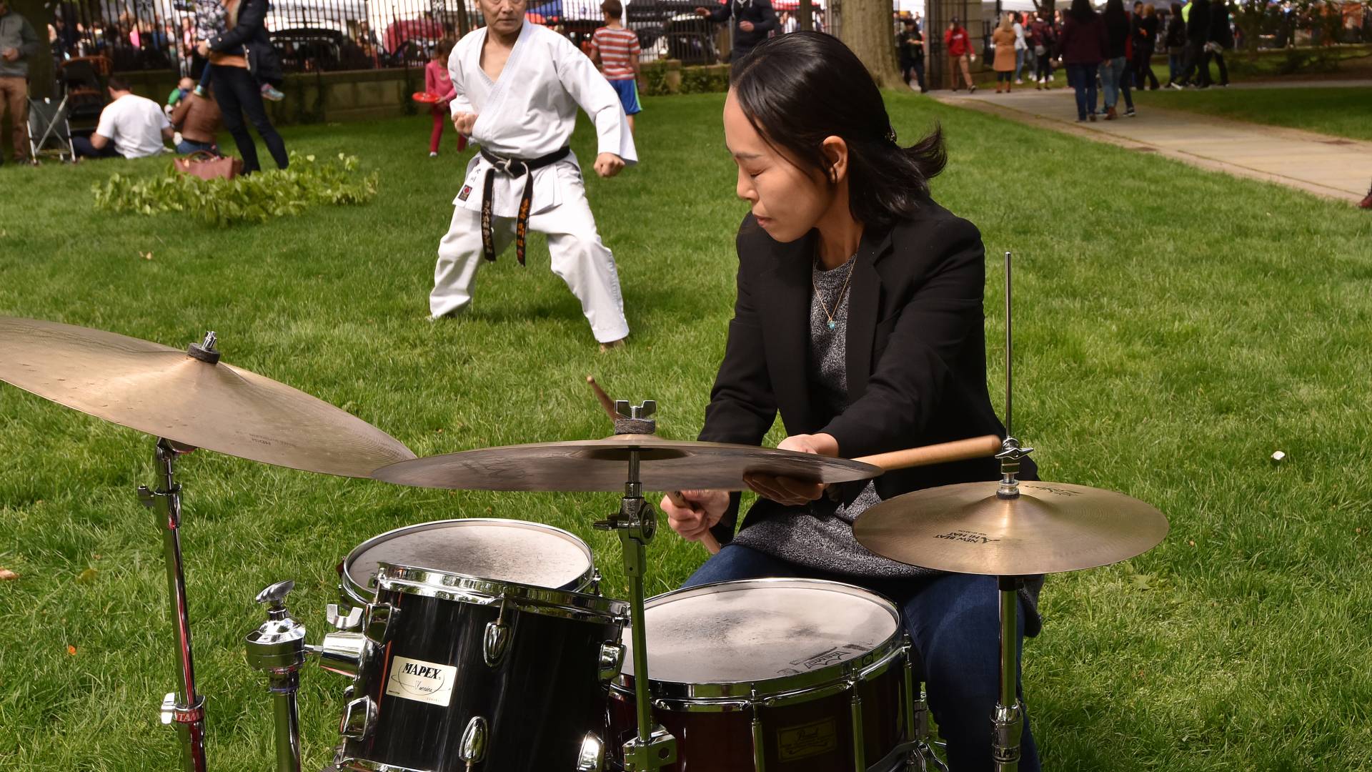 A man demonstrates martial arts while a woman drums