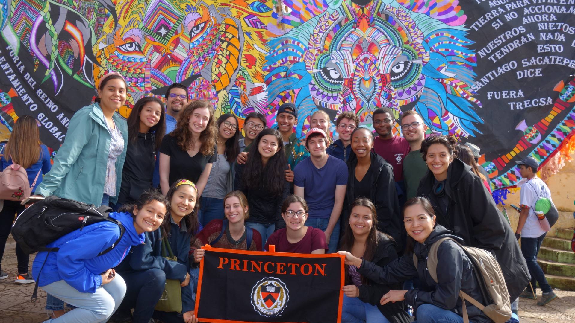 Students stand in front of an elaborately decorated kite while holding a Princeton University banner