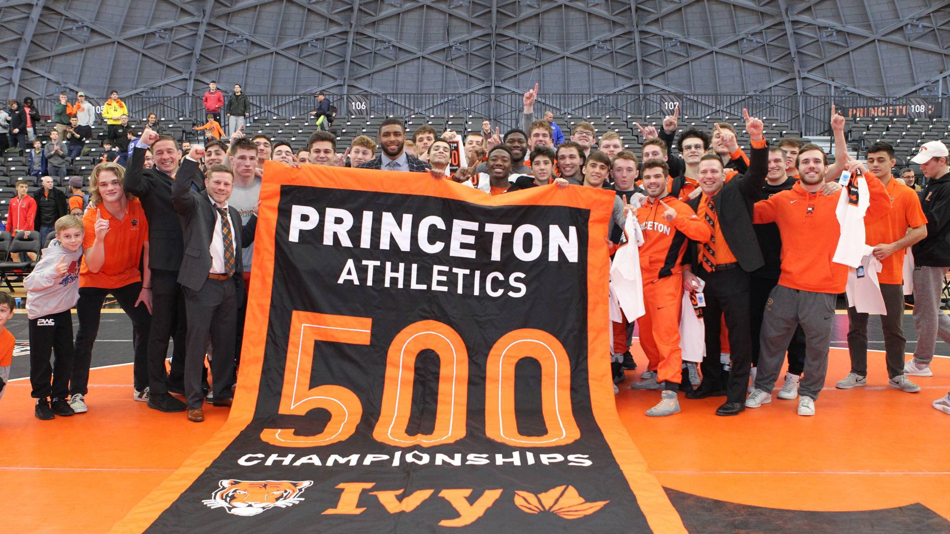 A group poses with a banner that reads, Princeton Athletics 500 Championships Ivy"