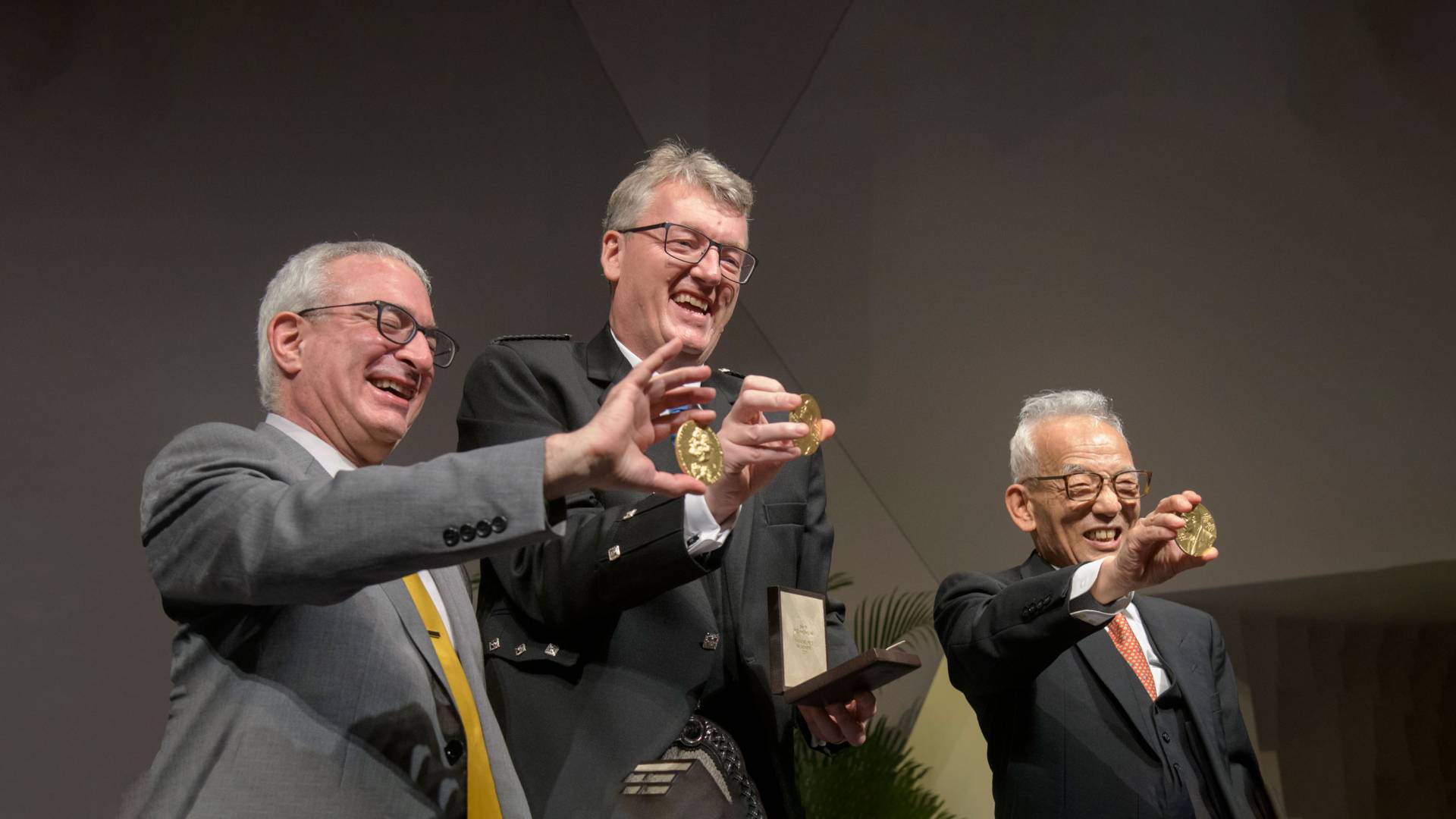 Angrist, MacMillan and Manabe hold up their newly-presented Nobel medals