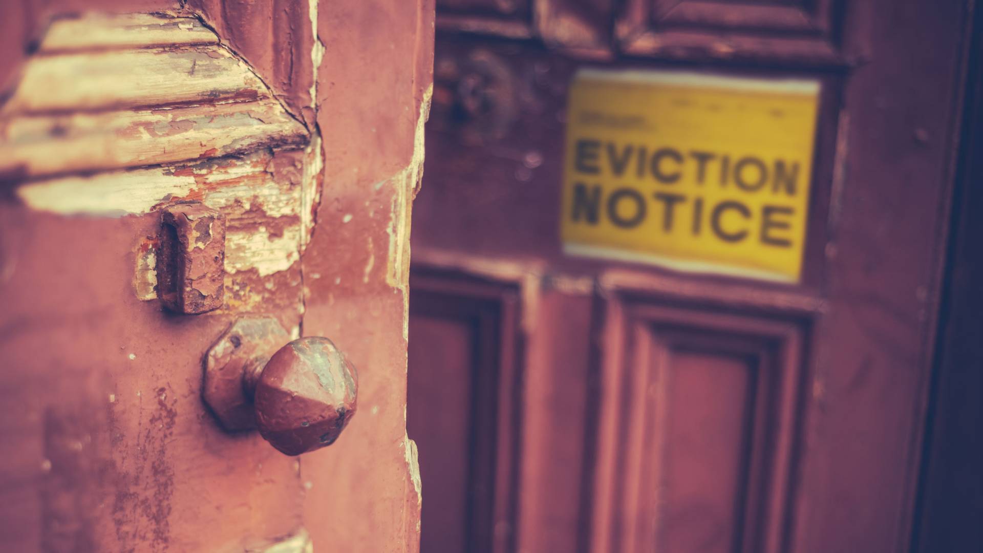 An eviction notice in a door with chipped paint