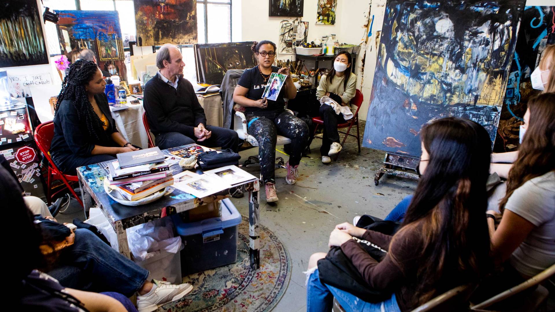 A painter presents her work surrounded by students and professors