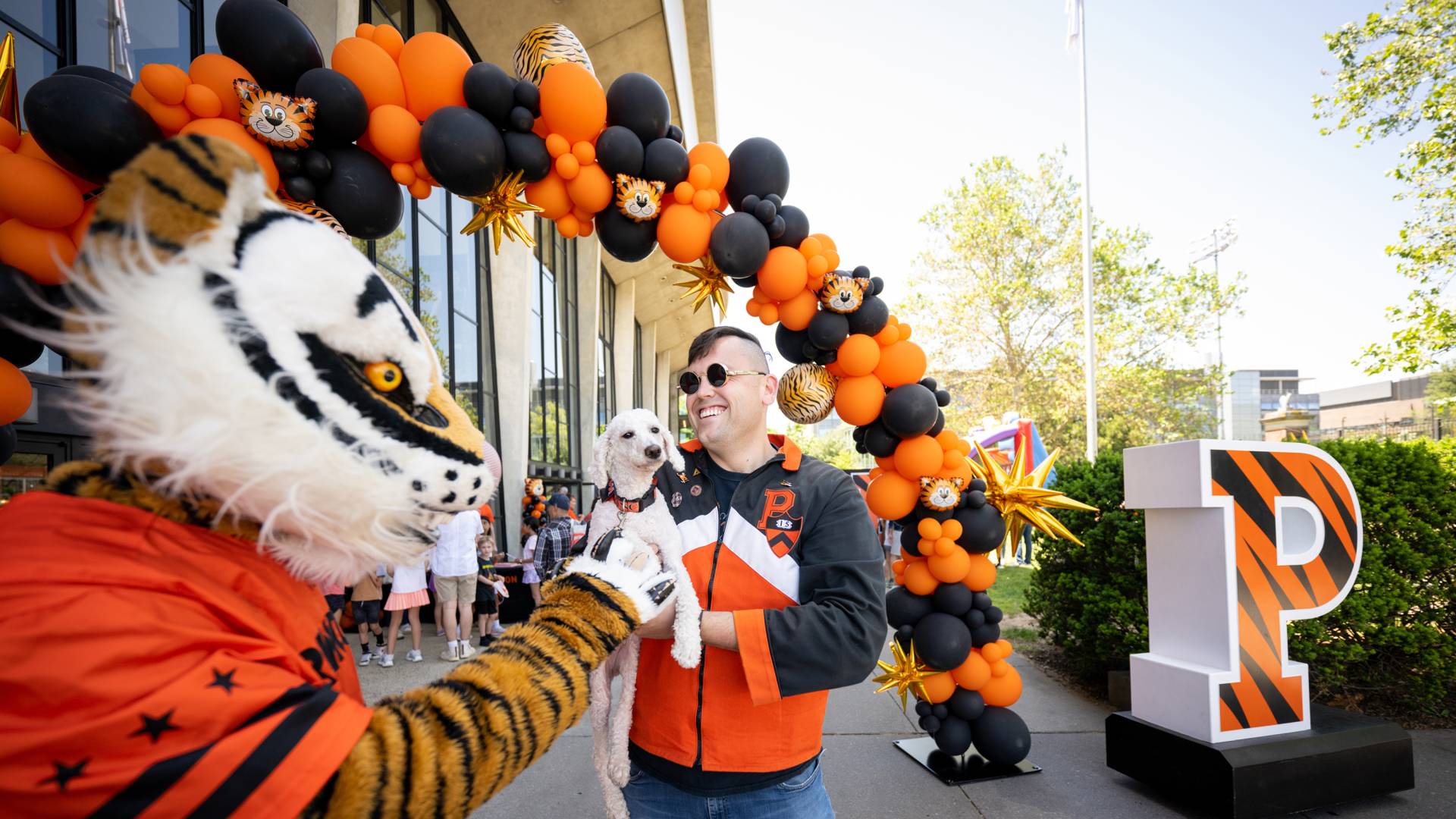 Tiger mascot, balloon arch, dog, alumnus, and tiger-striped intial P