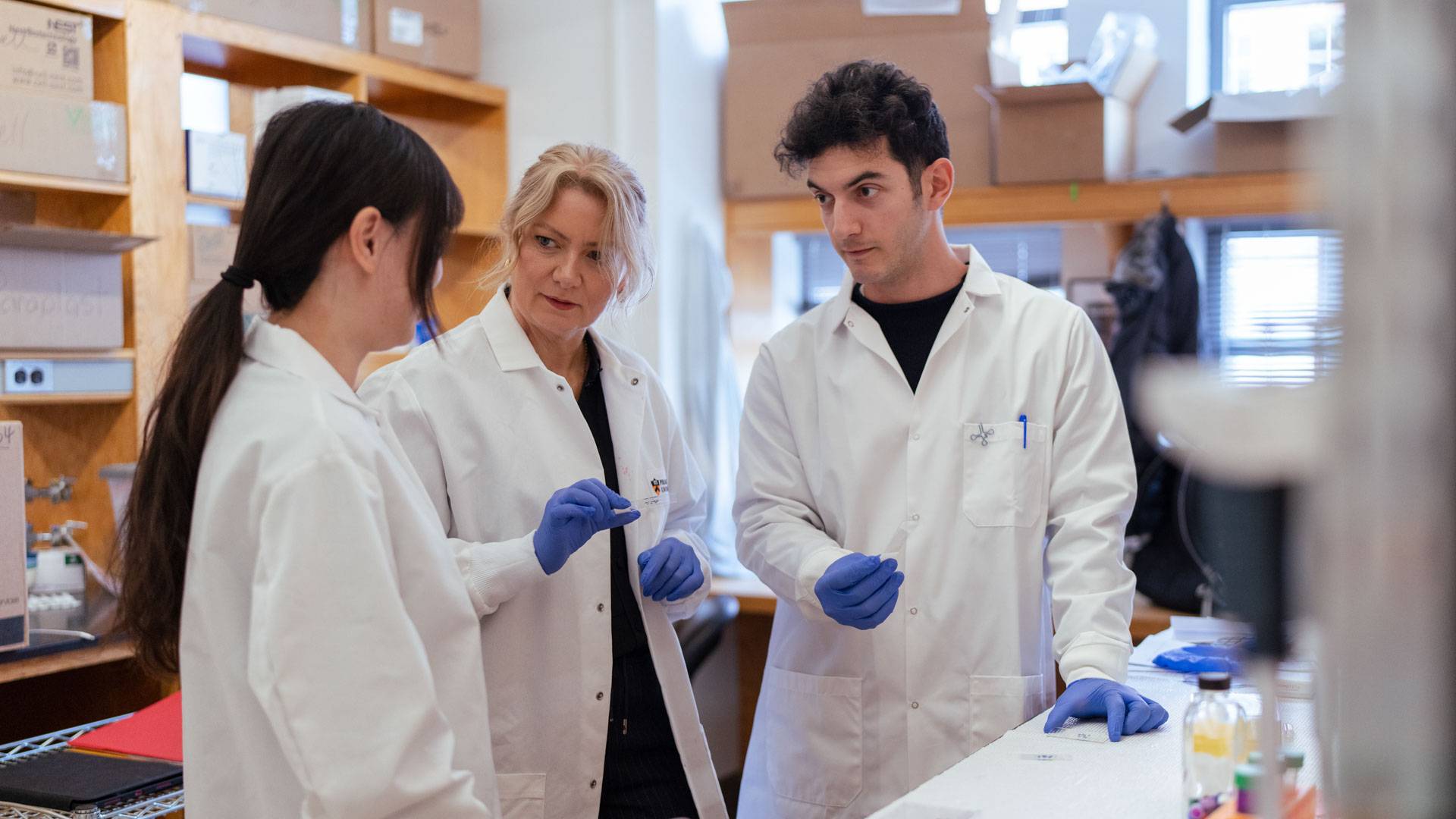 Lydia Lynch and two team members confer in the lab.
