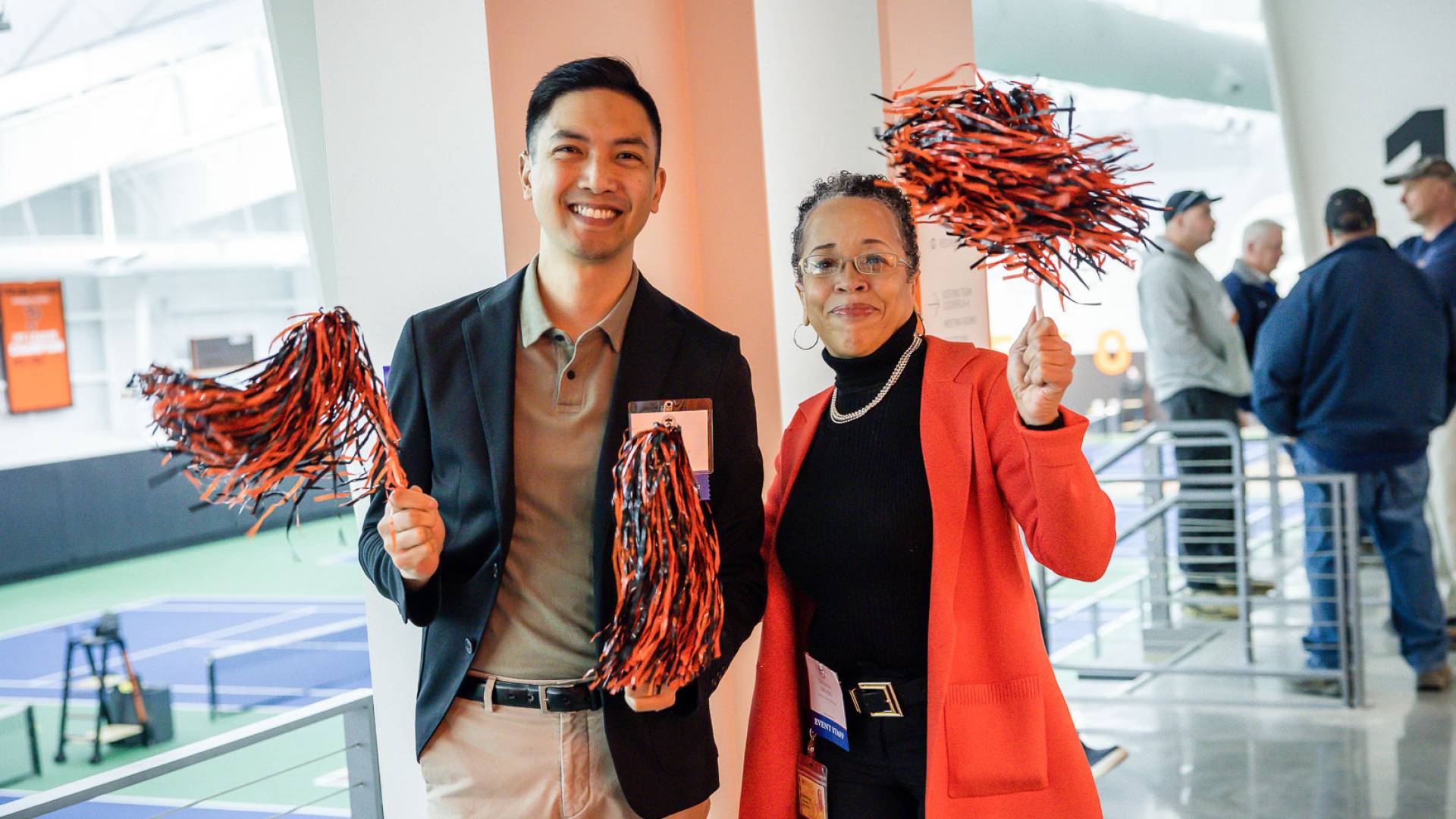 Staff members wave orange and black pom poms