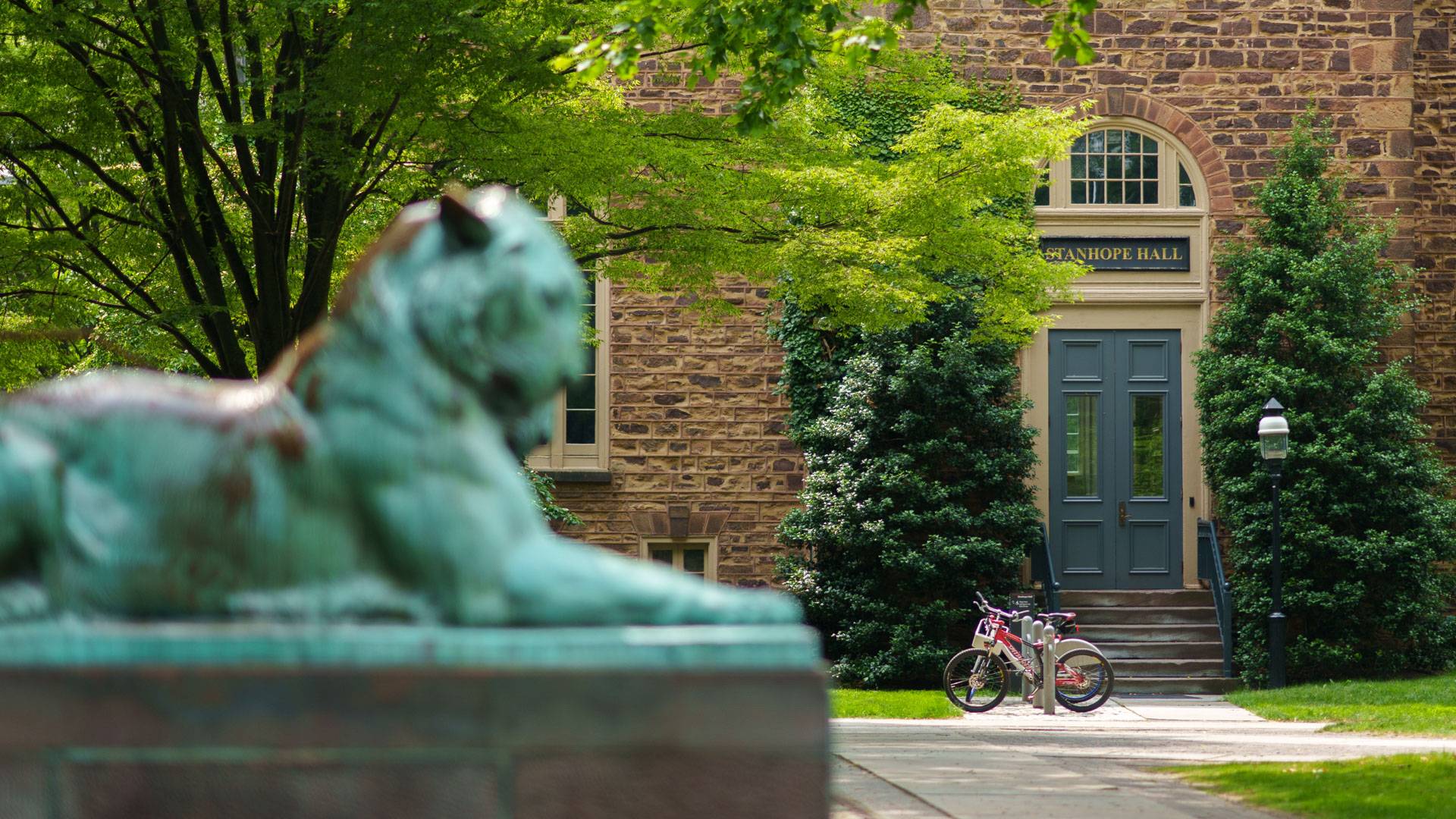 A bronze tiger sculpture in the foreground with Princeton's Stanhope Hall