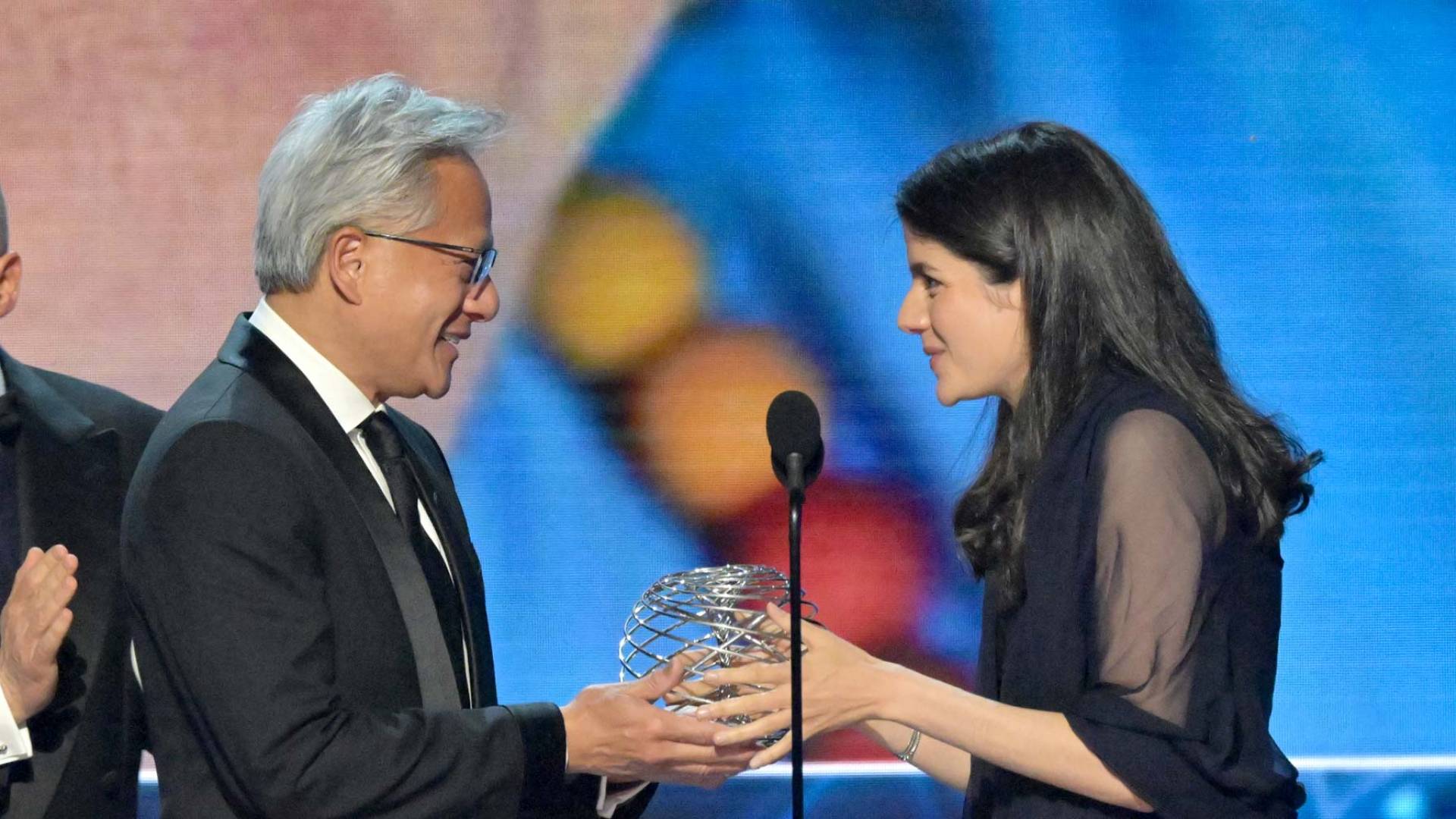Jensen Huang hands an award trophy to Carolina Figueiredo