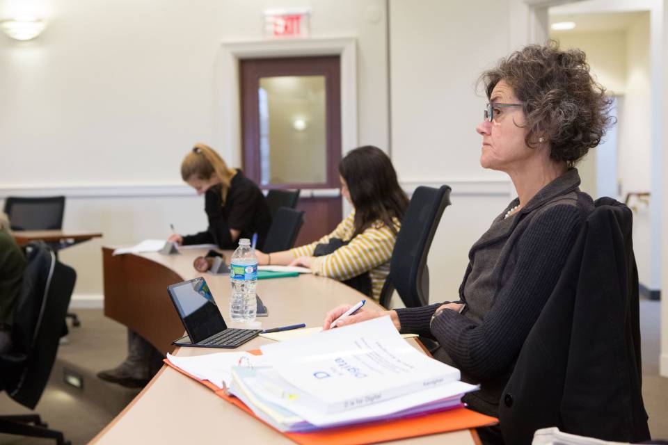 Participant in Community College Faculty Program sits and takes notes during a lesson