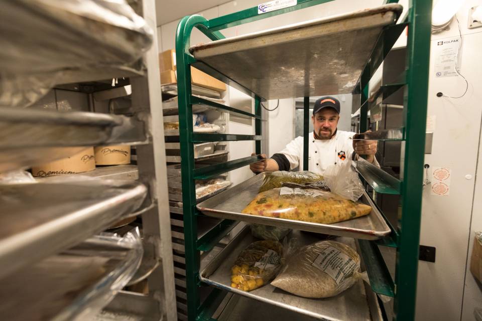 Chef Dan Maher moving rack of food going to freezer