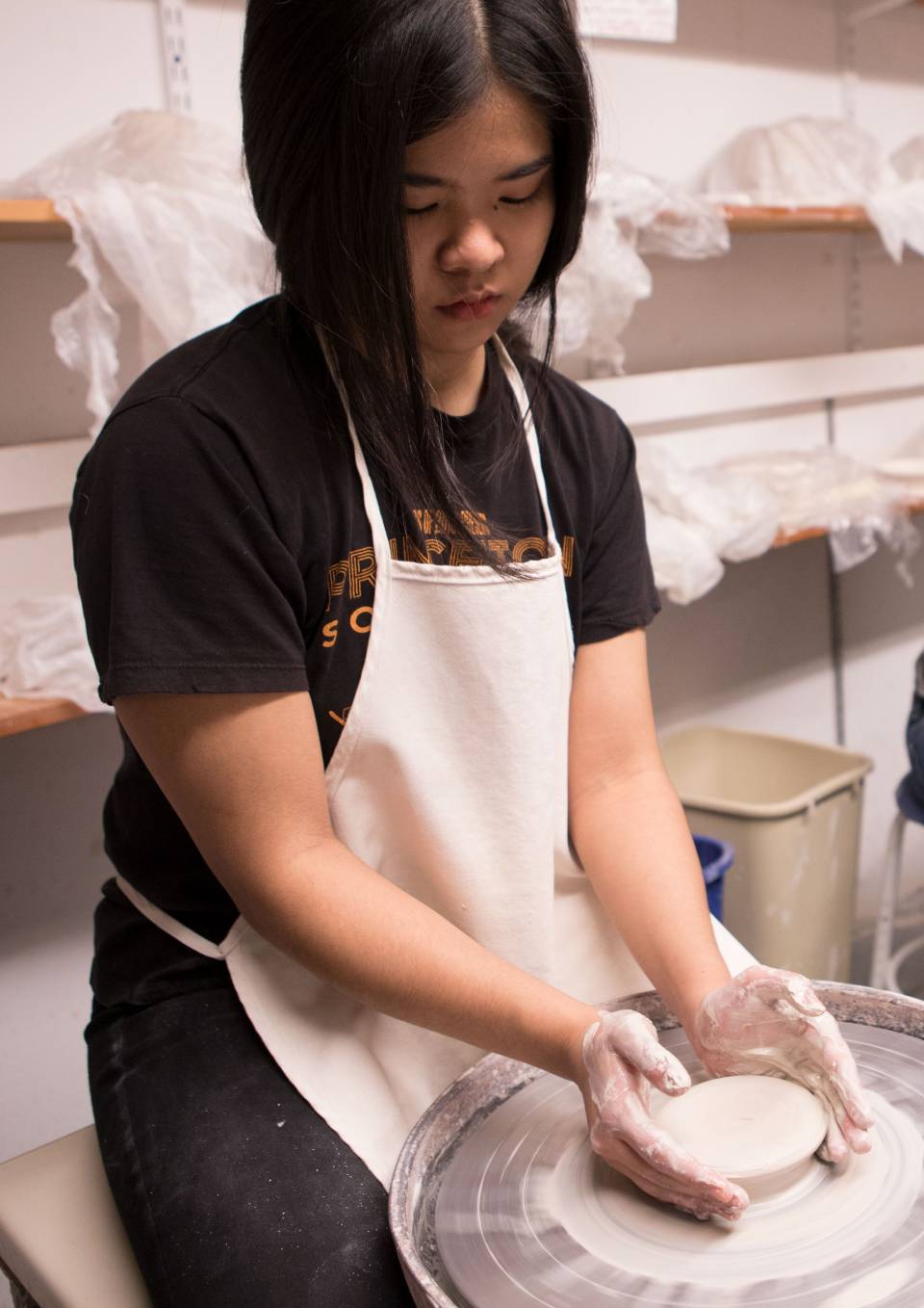 Student making clay bowl on wheel