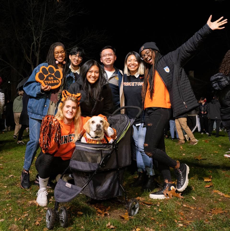 Students posing with a dog in a stroller at the 2021 bonfire on Cannon Green.