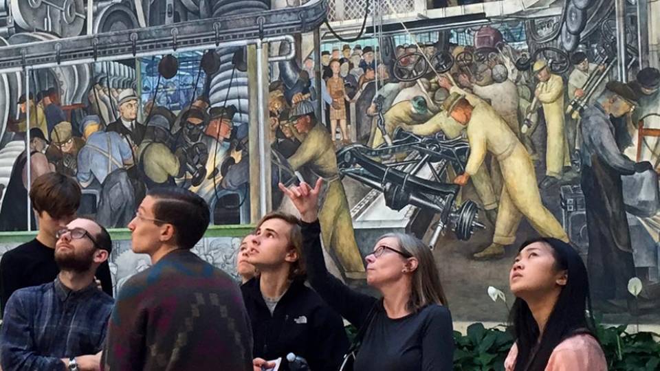 Professor Judith Hamera explains part of Diego Rivera's Detroit Industry fresco cycle to students during a visit to the Detroit Institute of Arts. 