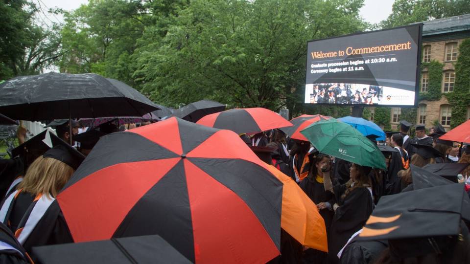 Graduates at the 2015 Commencement hold umbrellas.