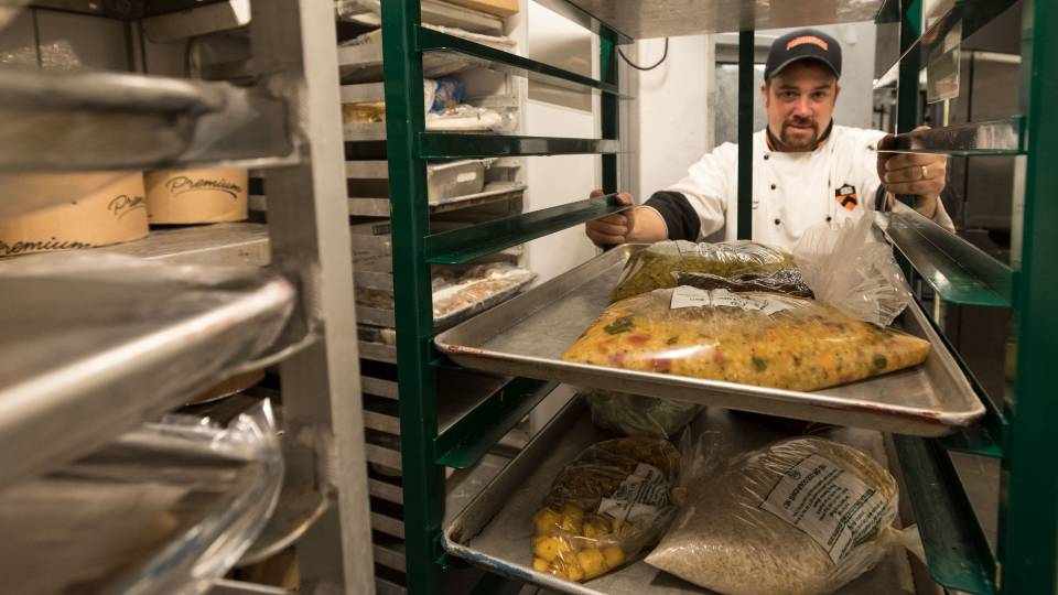 Chef Dan Maher moving rack of food going to freezer