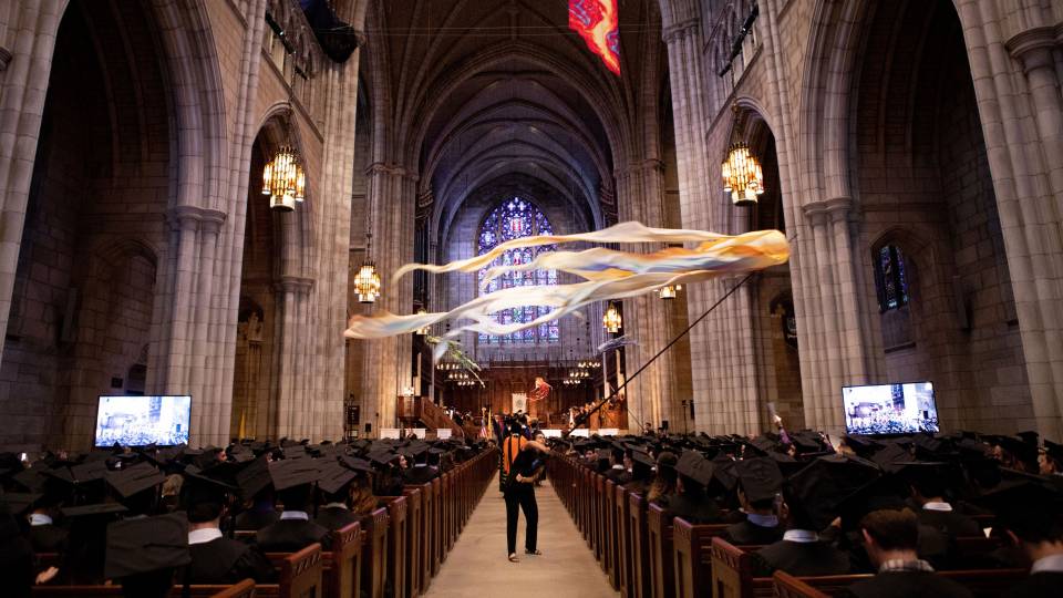 Students sitting in chapel while flag waves during Baccalaureate