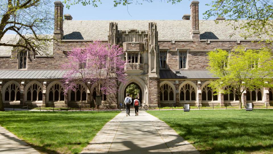 Two students walking toward arch on campus