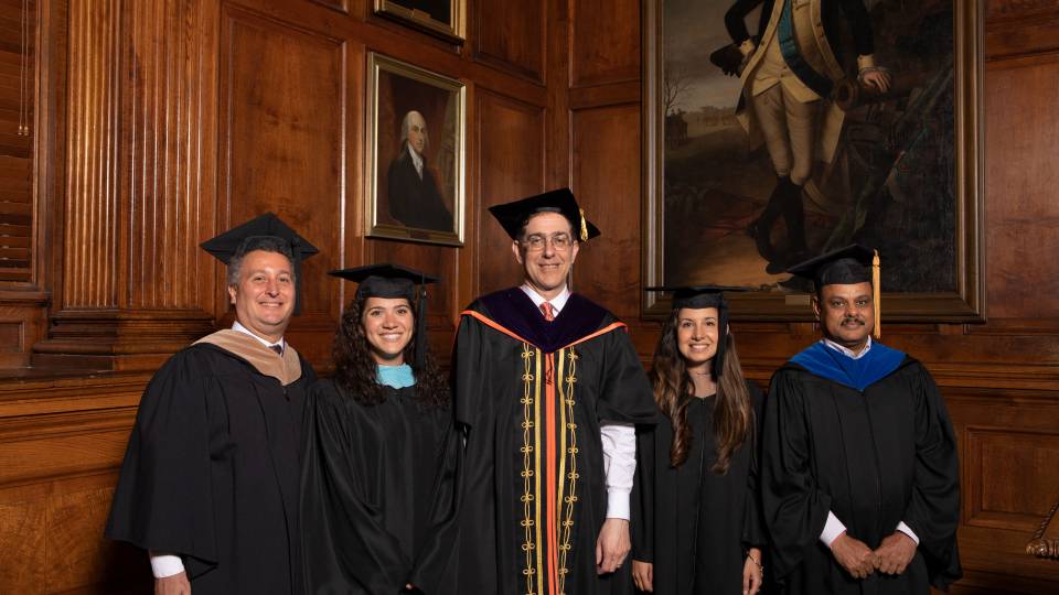 Kevin Killian, Kimberly Dickstein, Petrina Plunkett and Dr. Arun Srivastava pose with Christopher L. Eisgruber in ceremonial black gowns and mortarboards
