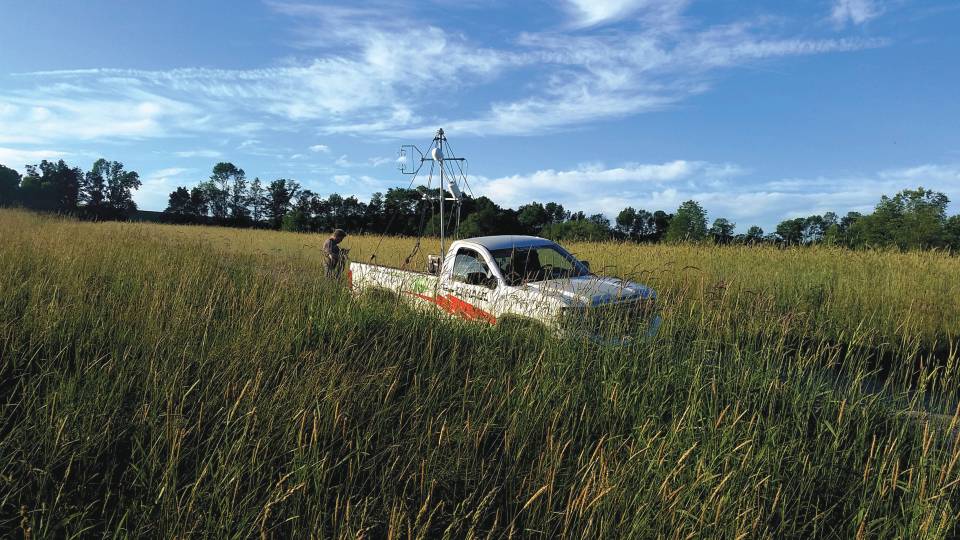A researcher in a field beside a mobile lab