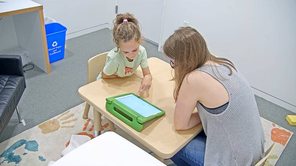 A child looks at a screen with a researcher