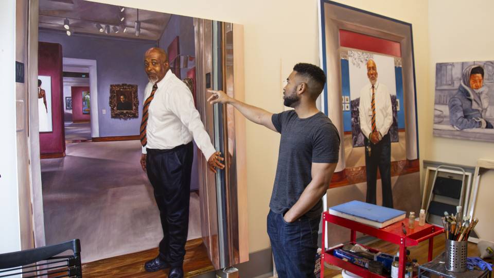 Mario Moore in studio pointing at painting