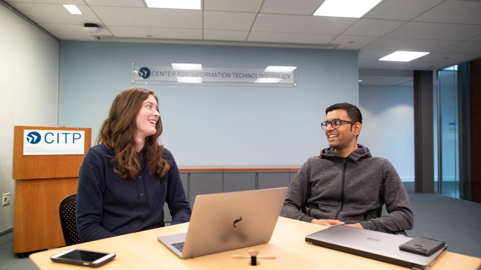 A graduate student and a professor speak over a laptop